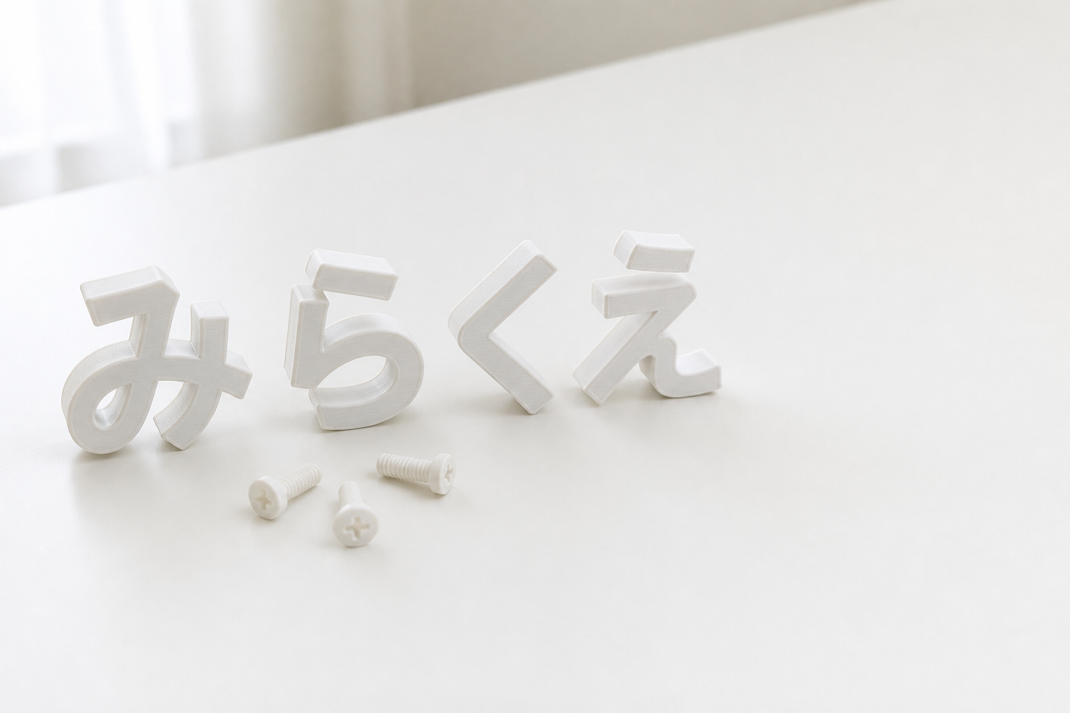 3Dプリントで作られた白い立体文字「みらくえ」と、3本の樹脂のねじ